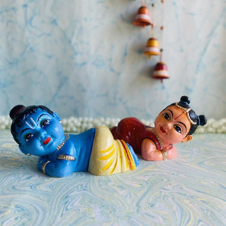 Handcrafted baby Radha Krishna Navaratri Golu dolls in vibrant colors, lying pose.