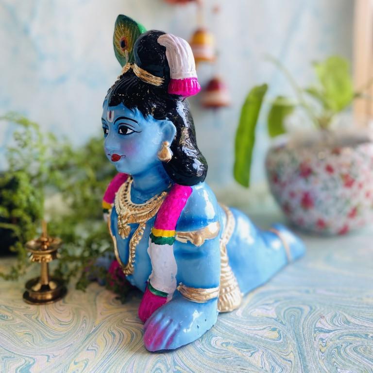 Handcrafted small infant Krishna idol in a crawling pose, vibrant blue with ornaments, for Navaratri Golu.