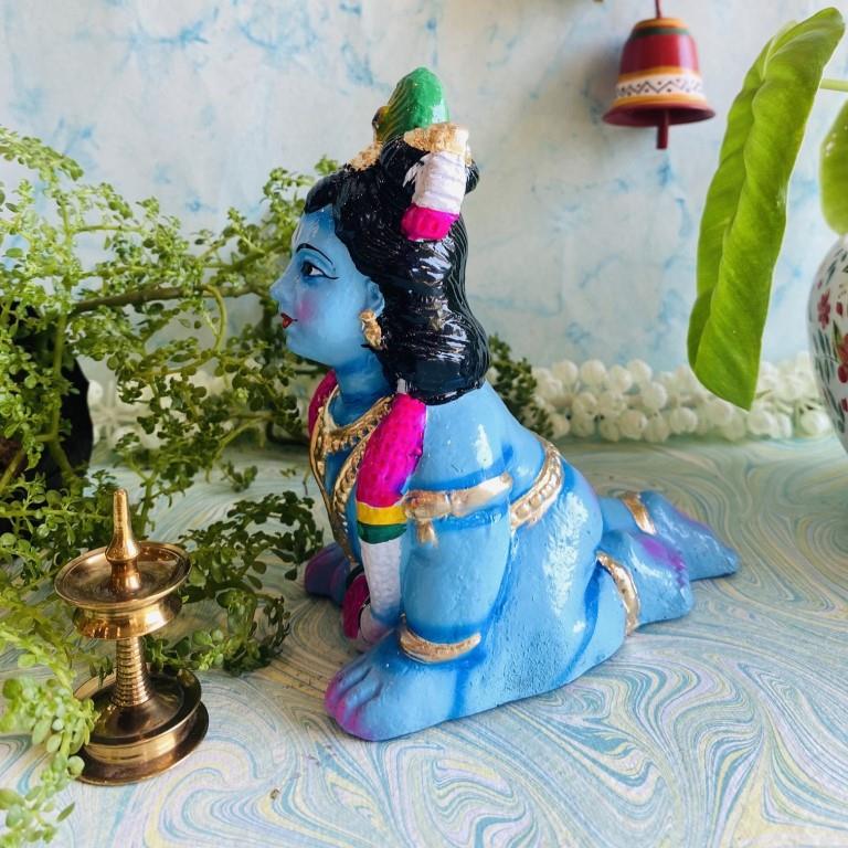 Handcrafted small infant Krishna idol in a crawling pose, vibrant blue with ornaments, for Navaratri Golu.