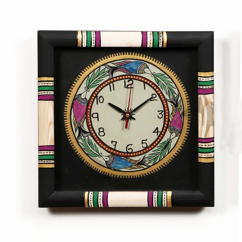 Handcrafted square wooden wall clock with colorful folk art motifs, black frame, and vibrant accents in pink, green, and gold.