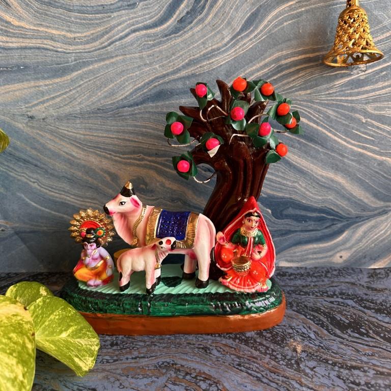 A Golu doll scene featuring Krishna and Yashodha under a tree, with a cow and calf, detailed in bright colors.