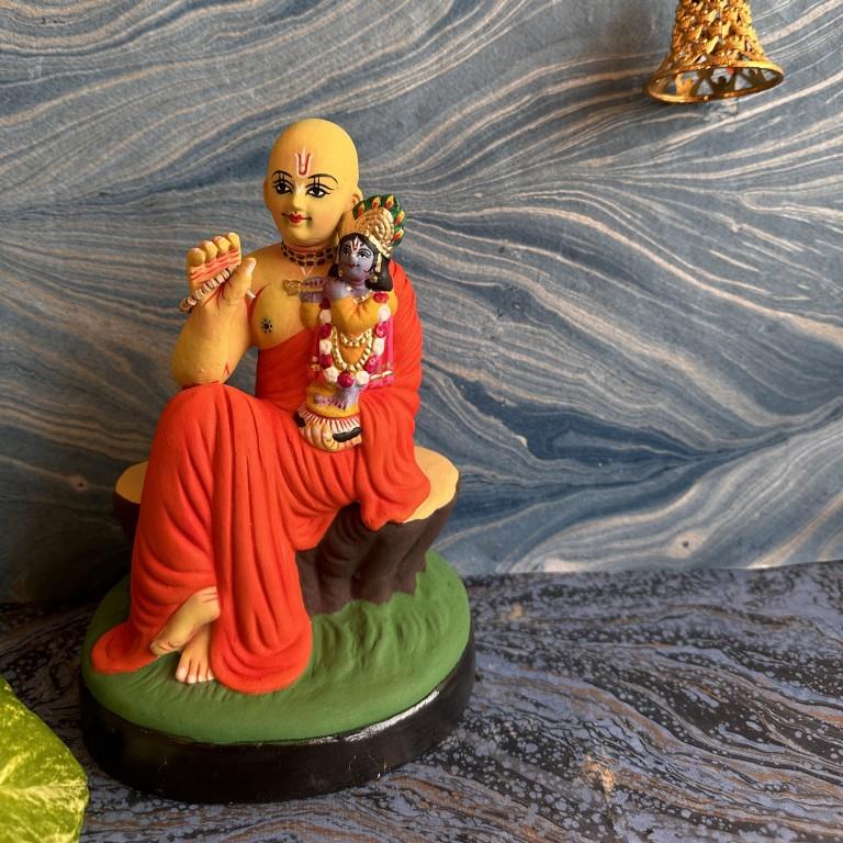 Handcrafted Golu doll of Chaitanya Mahaprabhu seated with Baby Krishna, showcasing detailed artistry and vibrant colors.