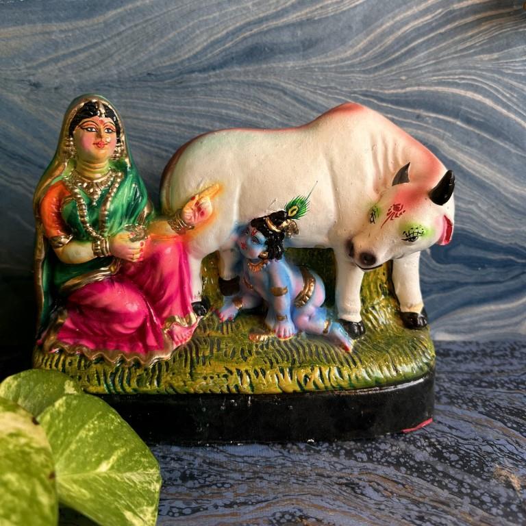 Handcrafted Golu doll set depicting Baby Krishna crawling, Yashoda seated, and a sacred cow, designed with vibrant colors and intricate detailing.