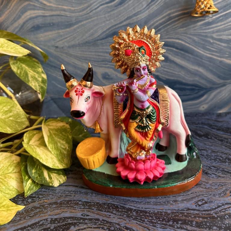 Handcrafted Navarathri Golu doll featuring Lord Krishna playing the flute beside a cow, adorned with vibrant colors and intricate detailing.