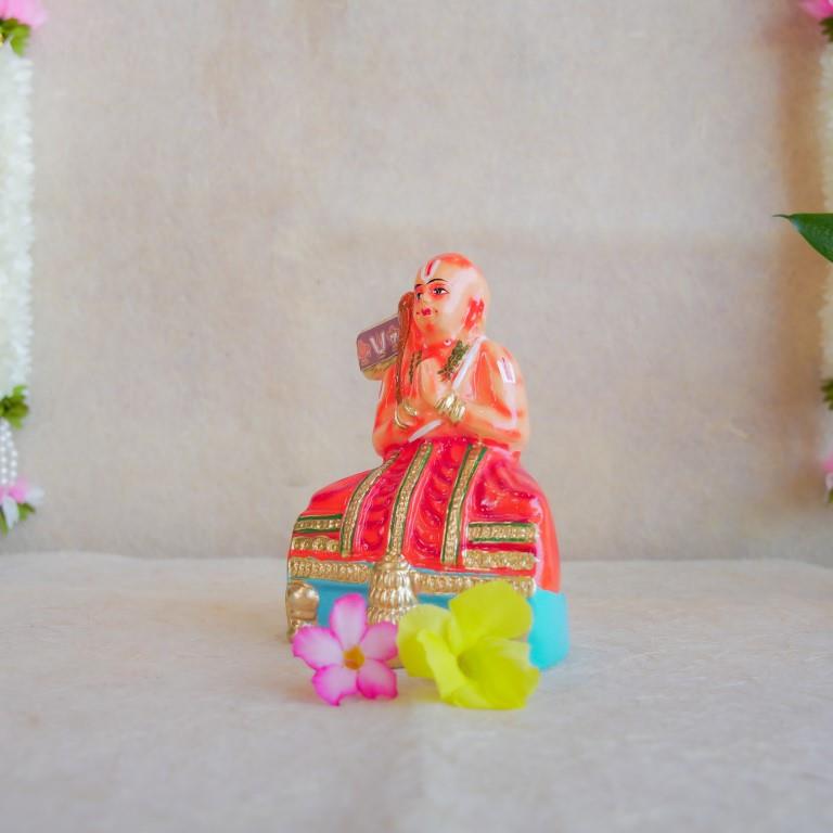 Hand-painted Navarathri Golu doll of Saint Ramanujar in a meditative pose, adorned in vibrant orange and gold attire.