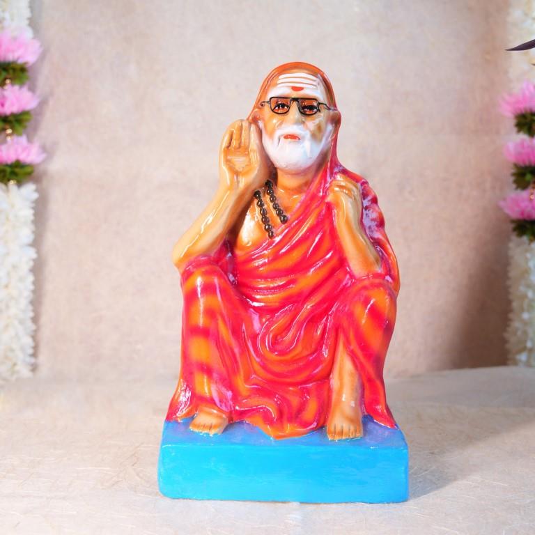 Handcrafted Navarathri Golu doll of Kanchi Periyavar seated in a calm posture, wearing an orange robe and spectacles.