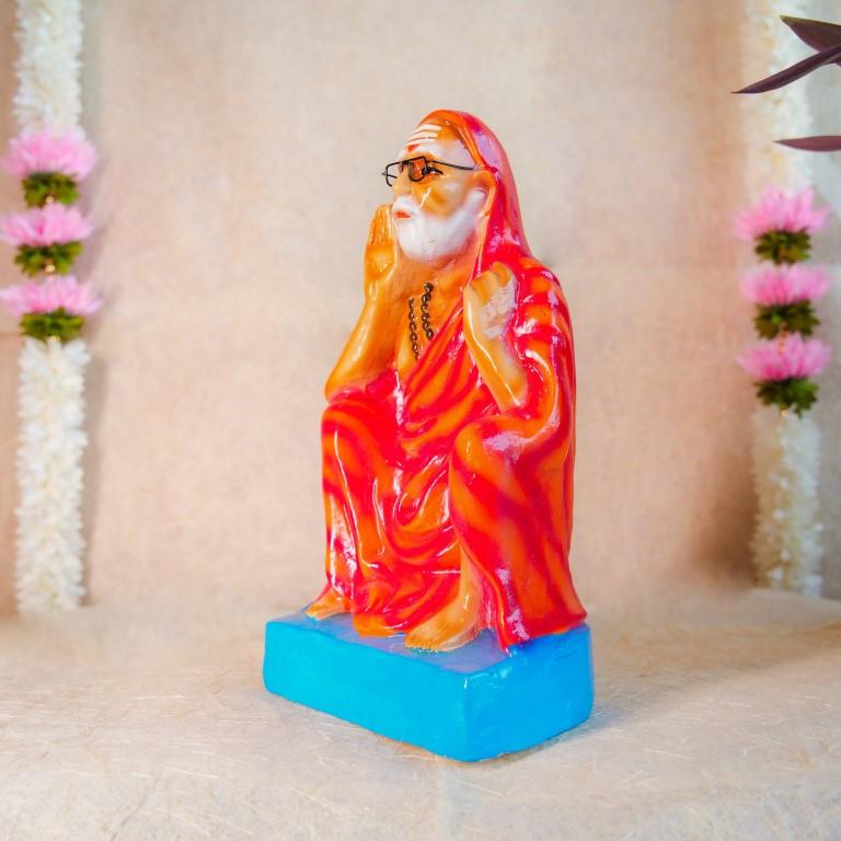 Handcrafted Navarathri Golu doll of Kanchi Periyavar seated in a calm posture, wearing an orange robe and spectacles.
