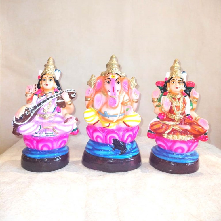 Navarathri Golu Dolls Set of Lakshmi, Ganesh, and Saraswati, hand-painted in vibrant colors with lotus base.