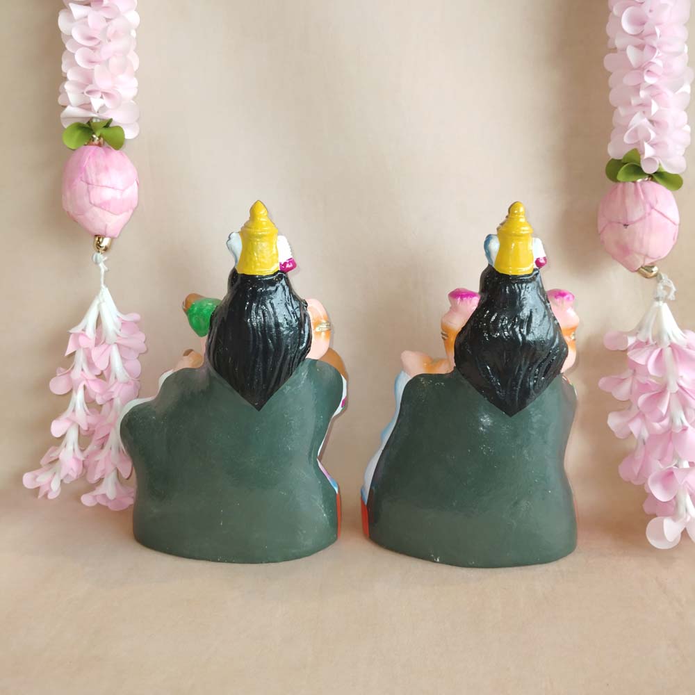 Handcrafted Lakshmi and Saraswathi Golu dolls set with vibrant colors, displayed with pink floral garlands.