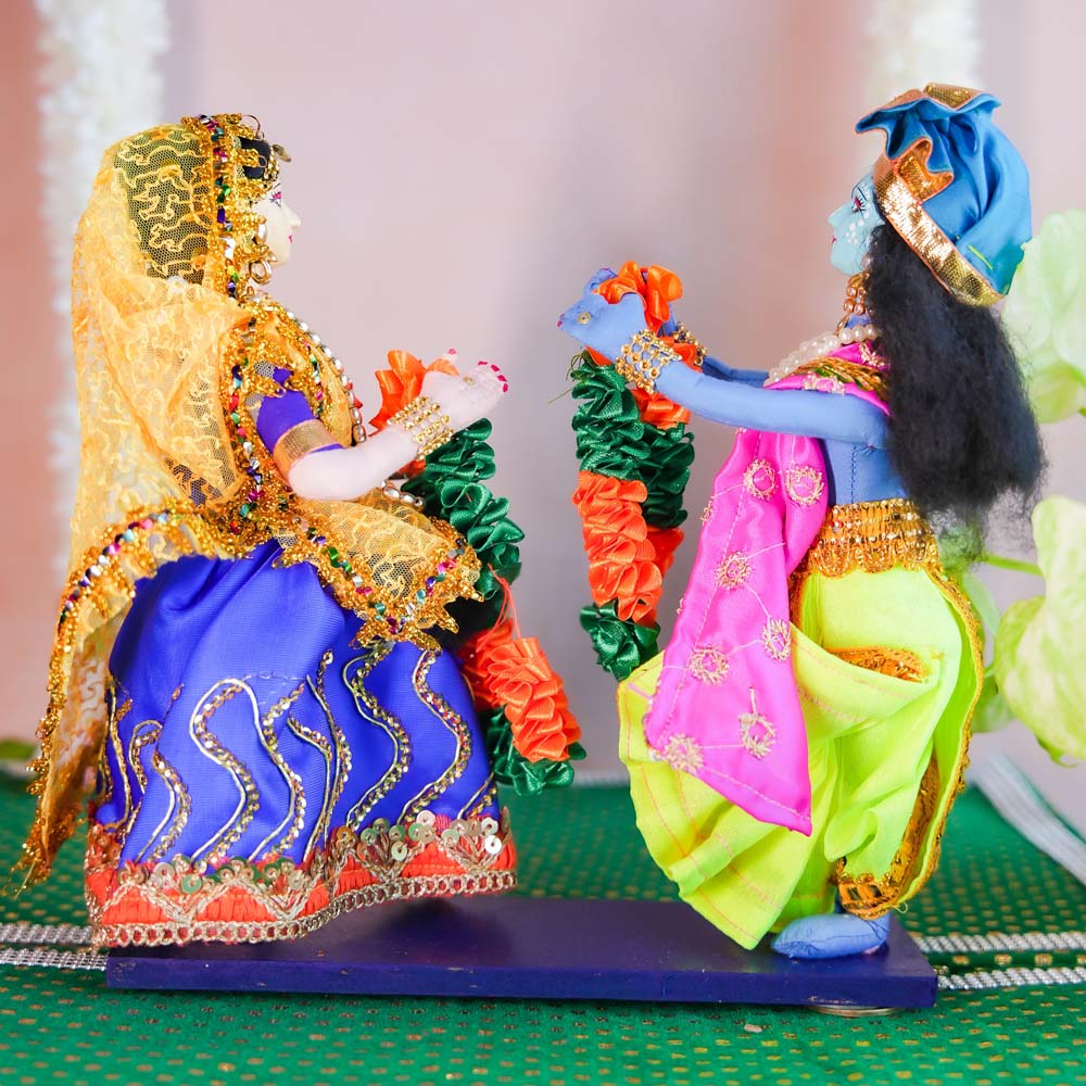 Handcrafted Radha and Krishna dolls exchanging garlands, dressed in colorful traditional attire with intricate details and floral accessories.