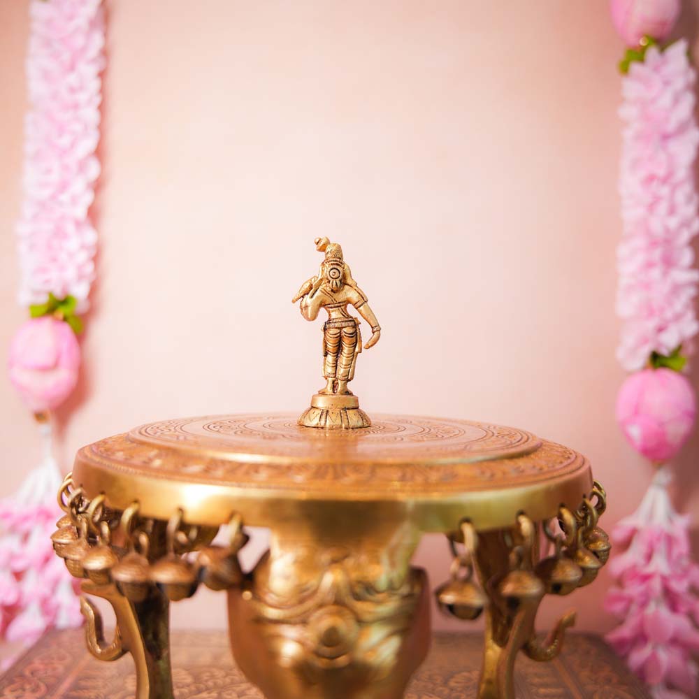Small brass Andal idol with intricate detailing, displayed on a decorative pedestal.