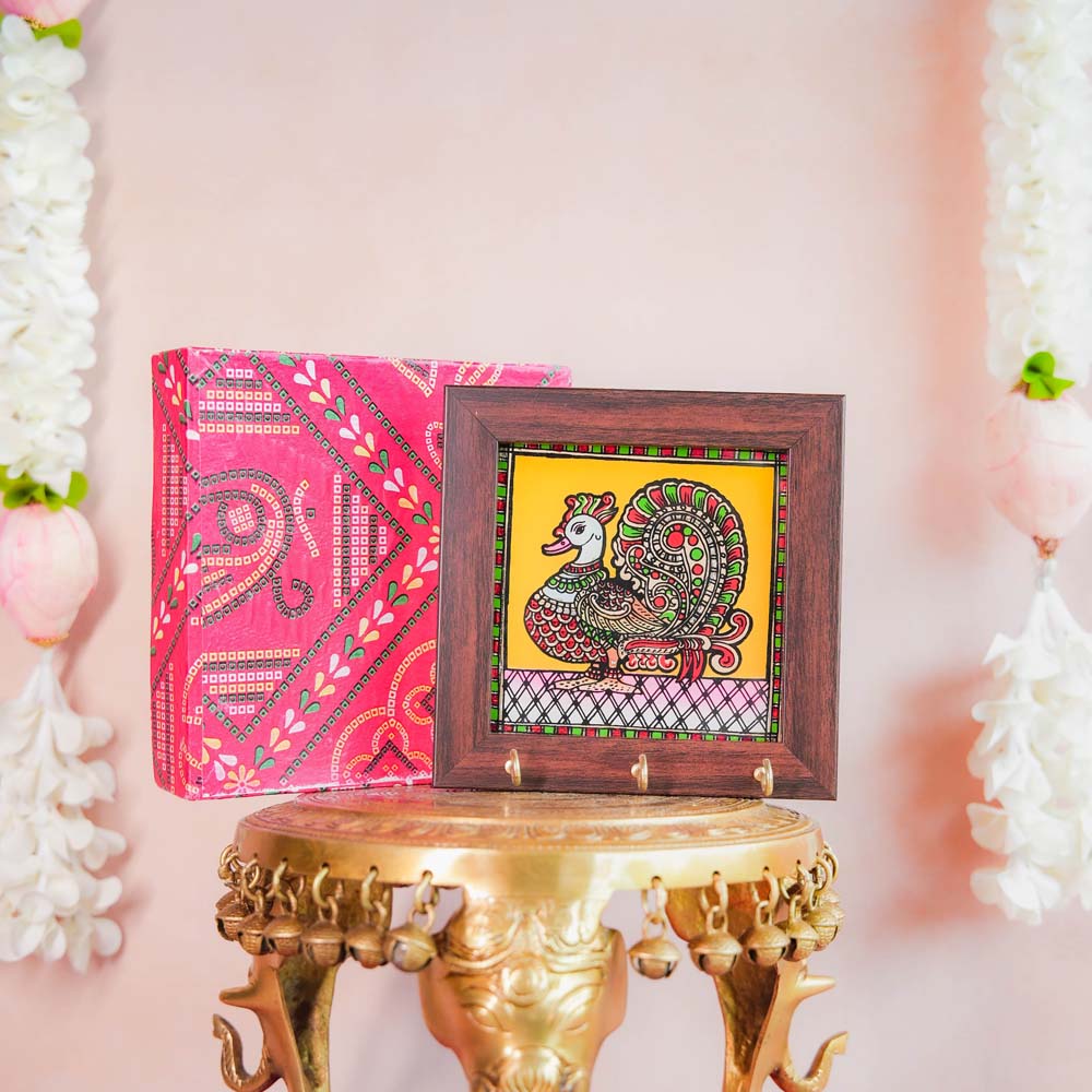 Decorative keyholder featuring a hand-painted Annam (mythical swan) design on a vibrant yellow background, framed with dark wood, and equipped with key hooks.