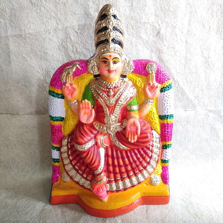 Araikasu Amman Navarathri Golu doll in a red saree and green blouse, seated under a decorative arch with detailed ornaments and vibrant colors.