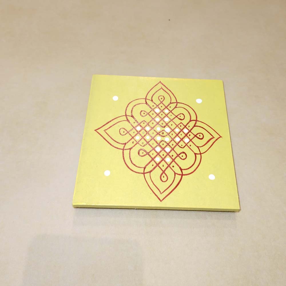 Yellow Kolam Manai platform with a red kolam design, used for traditional pooja and rituals.