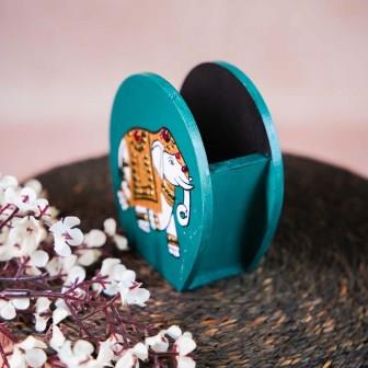Hand-painted wooden penstand with a decorative elephant design in white and gold on a teal background.