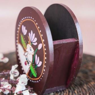 Hand-painted wooden penstand with a white cow design surrounded by lotus flowers, crafted on a brown background.