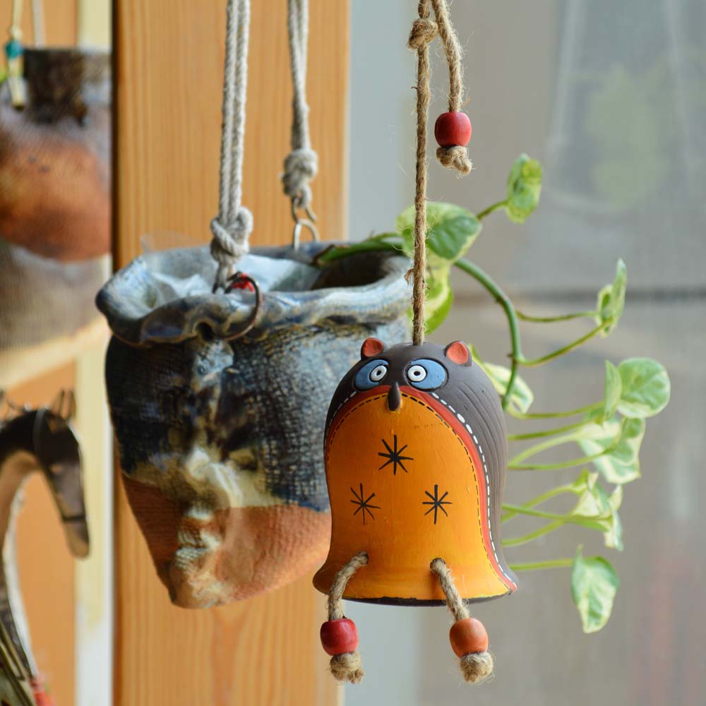 Handcrafted earthen hanging owl bell with orange and brown details, perfect for playful and artistic decor.