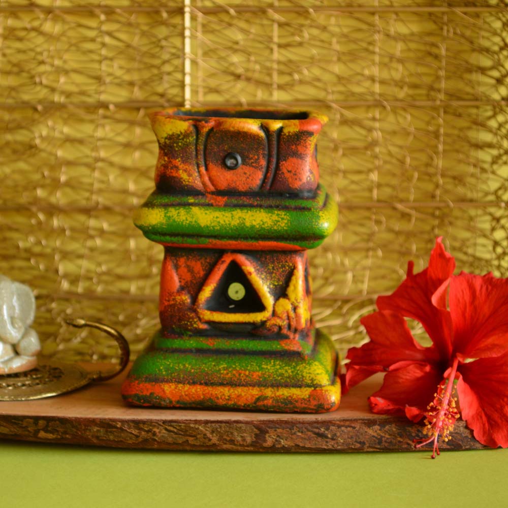 Handcrafted earthen mini Tulasi maadam with vibrant hand-painted design, placed against a natural background.