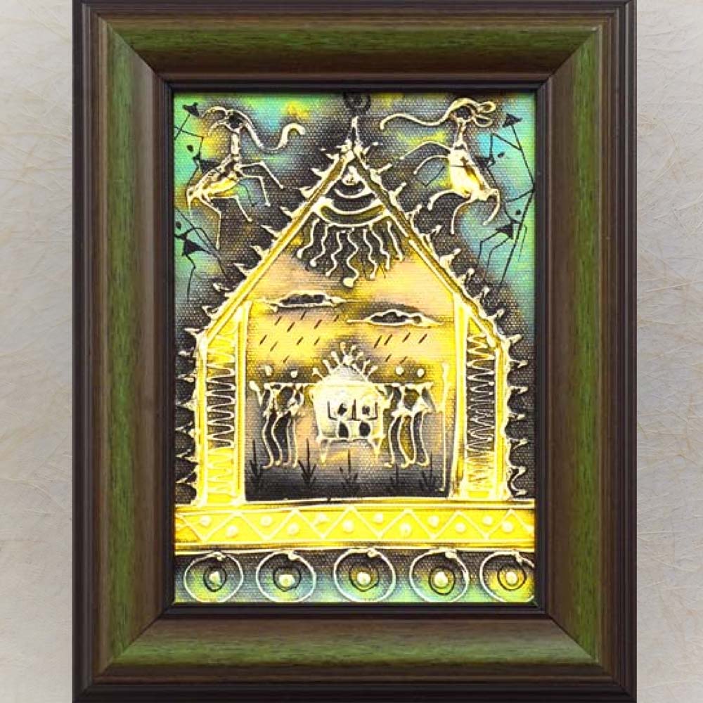 Framed Warli painting featuring a tribal hut, animals, and traditional patterns in gold, yellow, and green tones.