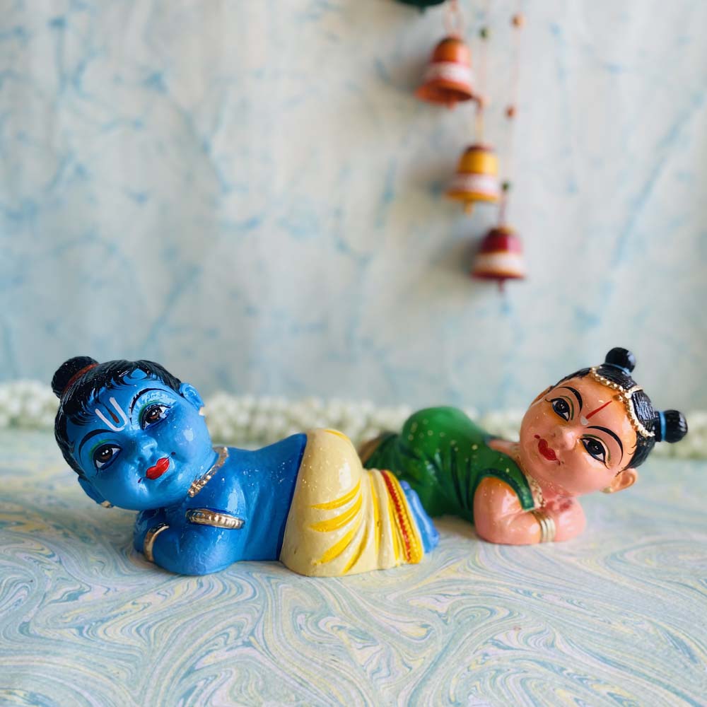 Handcrafted baby Radha Krishna Navaratri Golu dolls in vibrant colors, lying pose.