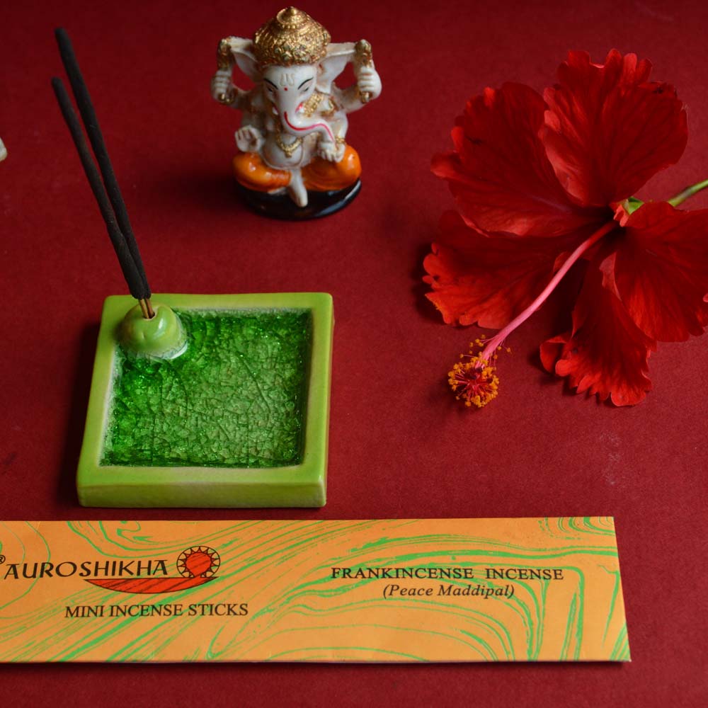 Cera Square Ceramic Incense Holder in vibrant green with Frankincense Mini Cones gift set, paired with a Ganesha figurine and a hibiscus flower on a red background.