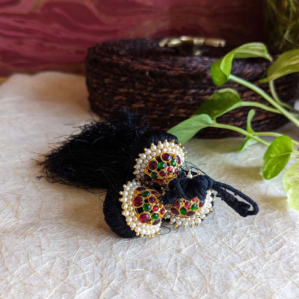 Kunjalam hair tassels with black threads, gold embellishments, red and green stones, and pearl accents in temple jewelry design