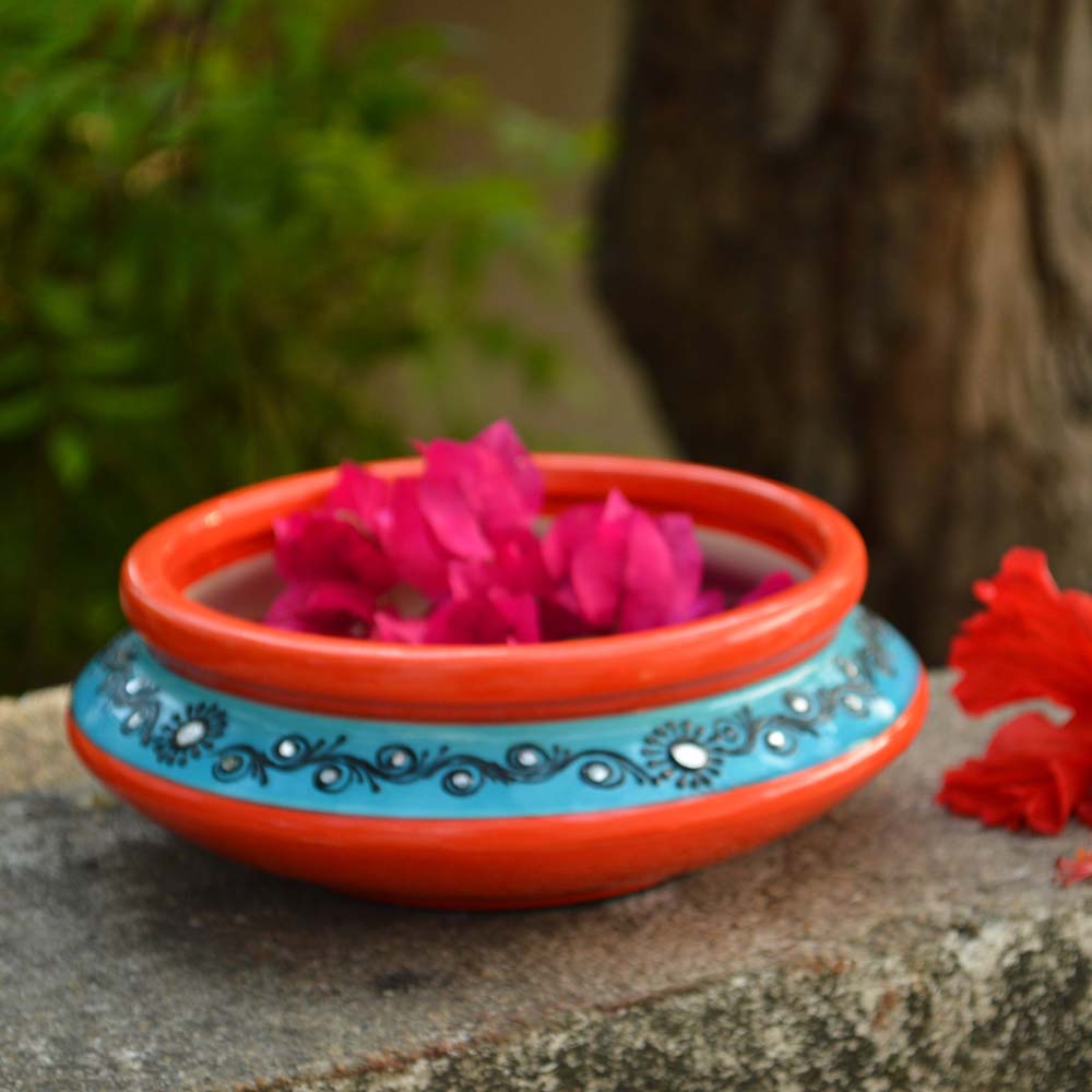 Handcrafted 6-inch multicolor earthen urli with intricate floral patterns and floating pink flowers, set against a natural outdoor backdrop.