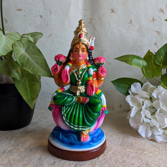 Hand-painted Goddess Lakshmi Golu doll seated on a lotus, featuring vibrant green and pink colors, crafted for Navaratri festival decor.