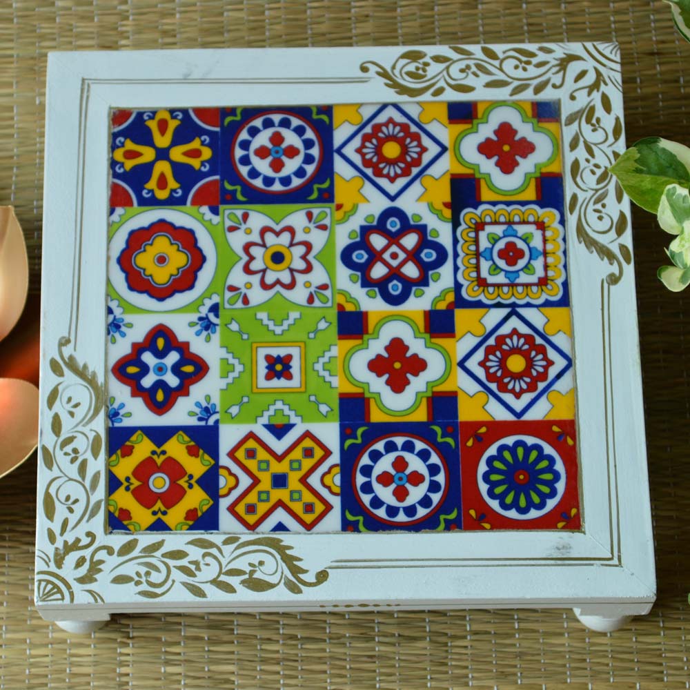 Handcrafted rectangular wooden stool with colorful ceramic tile top, showcasing vibrant patterns, placed on a woven mat.