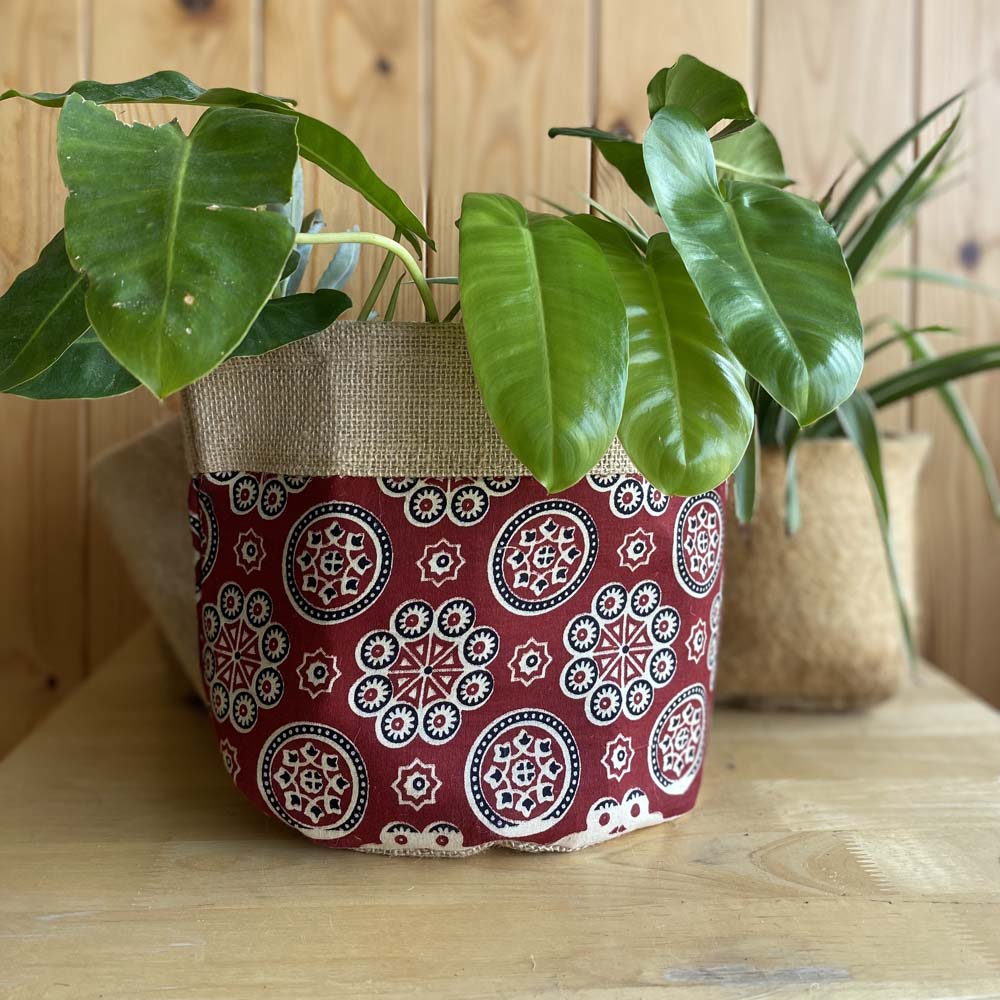 Natural jute plant holder with a vibrant Red Kolam print, designed for indoor plants and eco-friendly decor.