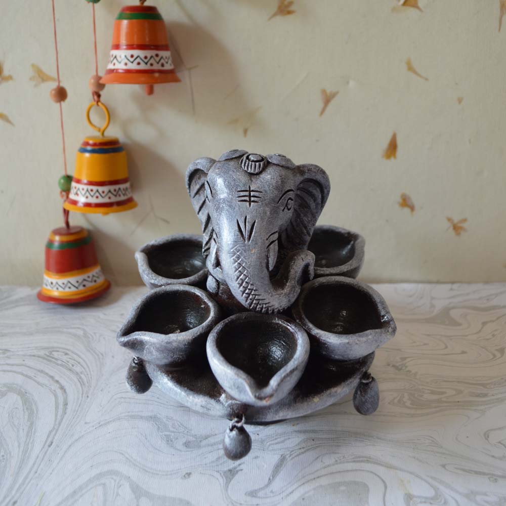 Handcrafted Ganesha lamp with a rustic finish and multiple oil holders for traditional pooja decor.