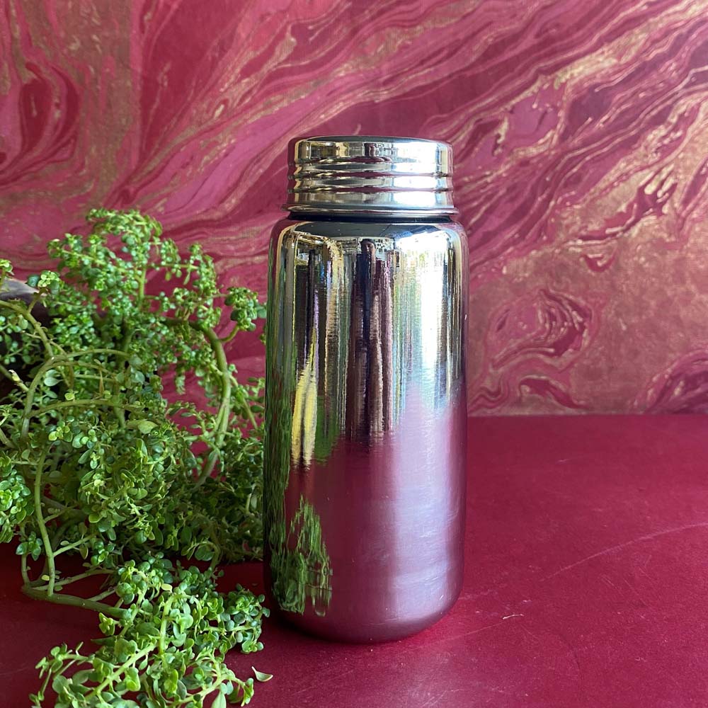 Sleek stainless steel bottle with a polished finish, 400ml capacity, placed against a vibrant background with green plants.