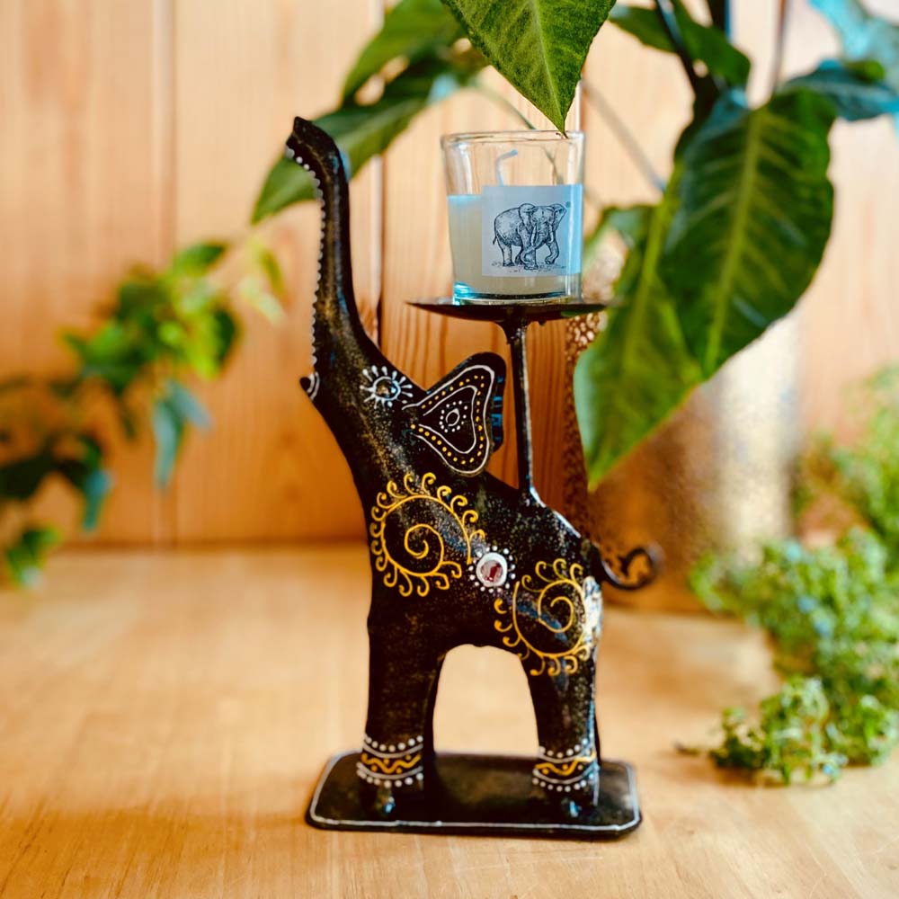 Handcrafted metal elephant-shaped T-light holder in black with intricate gold and colorful accents, featuring an elevated candle platform.
