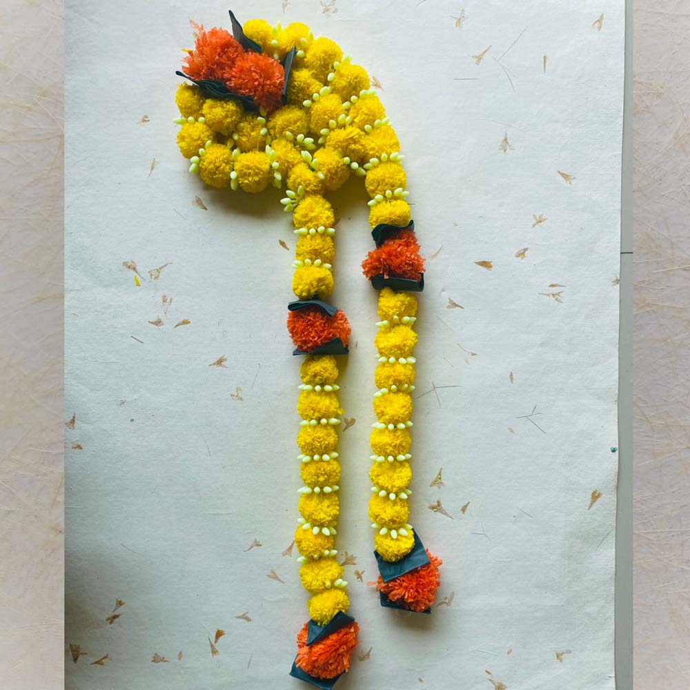 Big Laddu single-string garland in yellow and orange with white bud accents and green leaves, perfect for traditional Indian decor.
