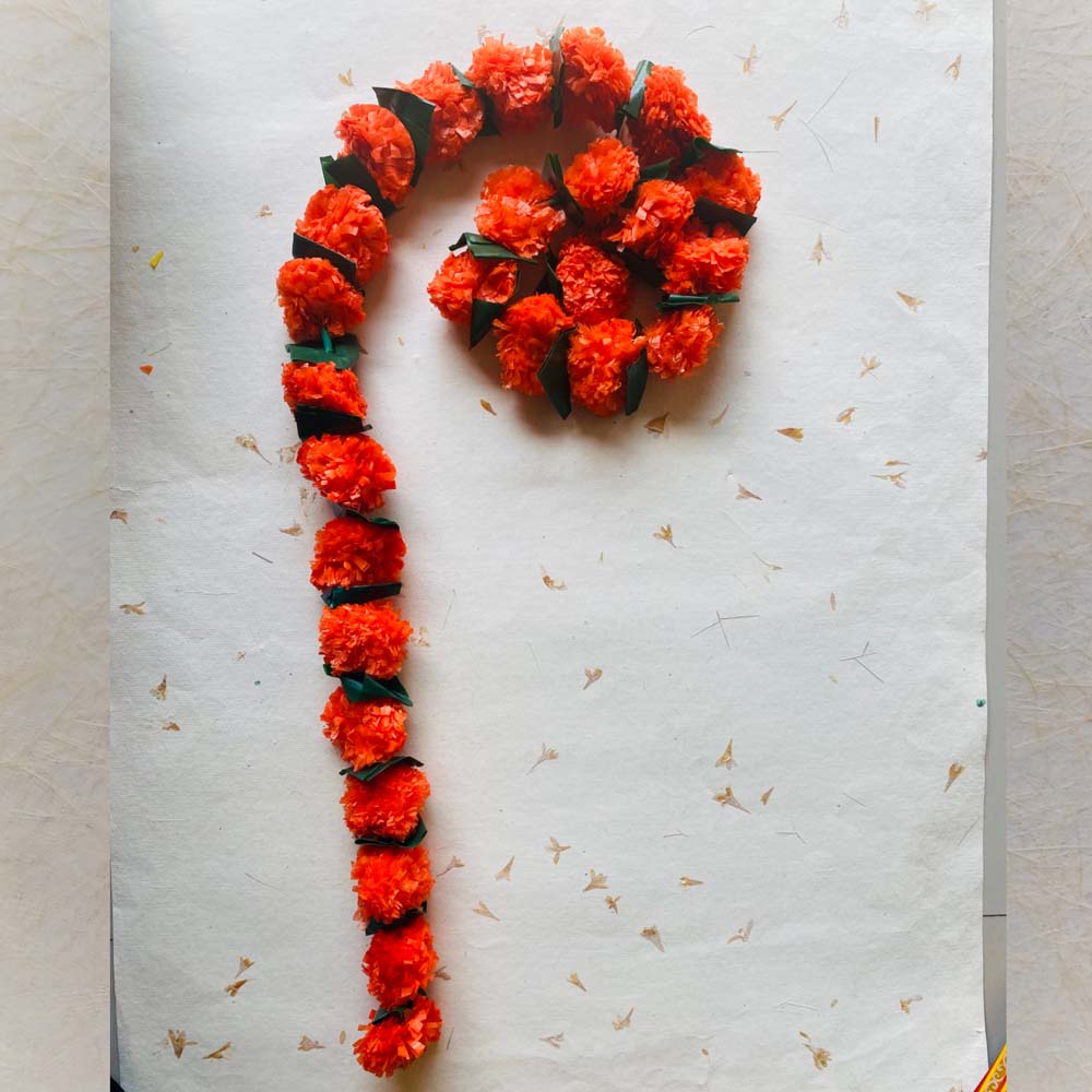 Saffron single-string garland with folded green leaves, ideal for festive and traditional Indian decor.
