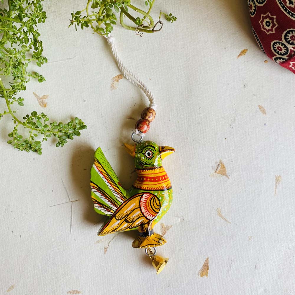Handcrafted light green wooden hanging sparrow decor with intricate traditional designs, beads, and a bell.
