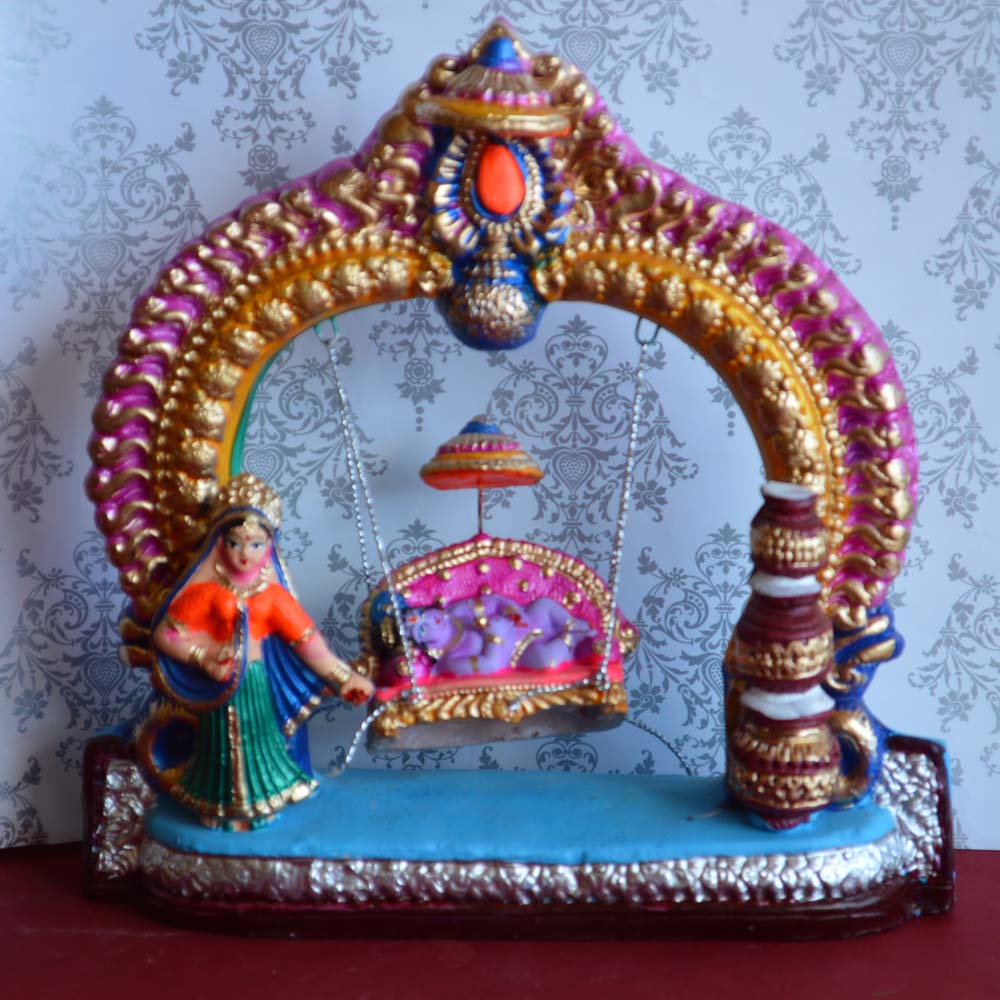 Handcrafted Krishna on a decorative swing figurine with vibrant colors and intricate detailing for traditional decor.