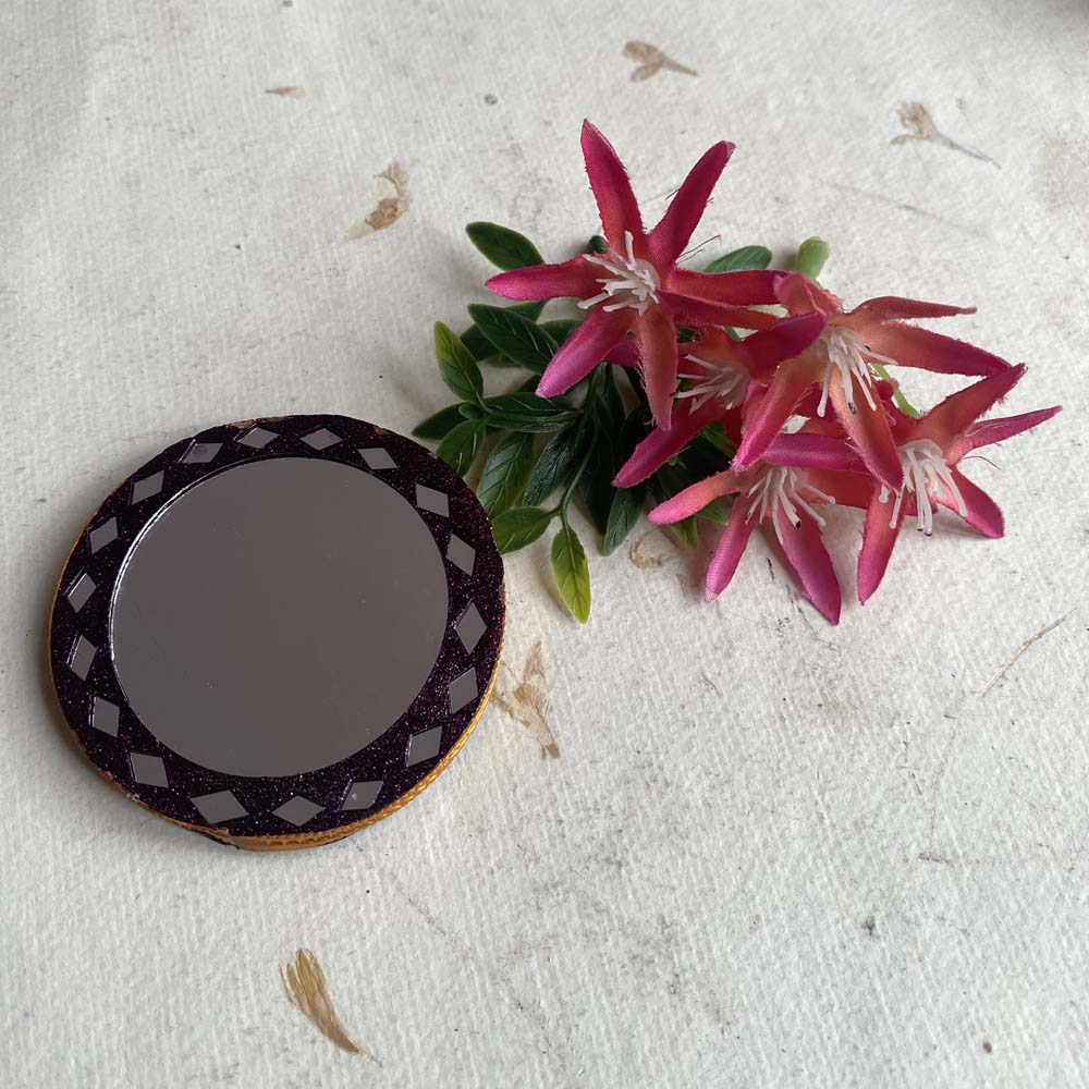 Round decorative mirror with a glittery border and geometric accents, ideal for pooja, home decor, or as a compact utility item.