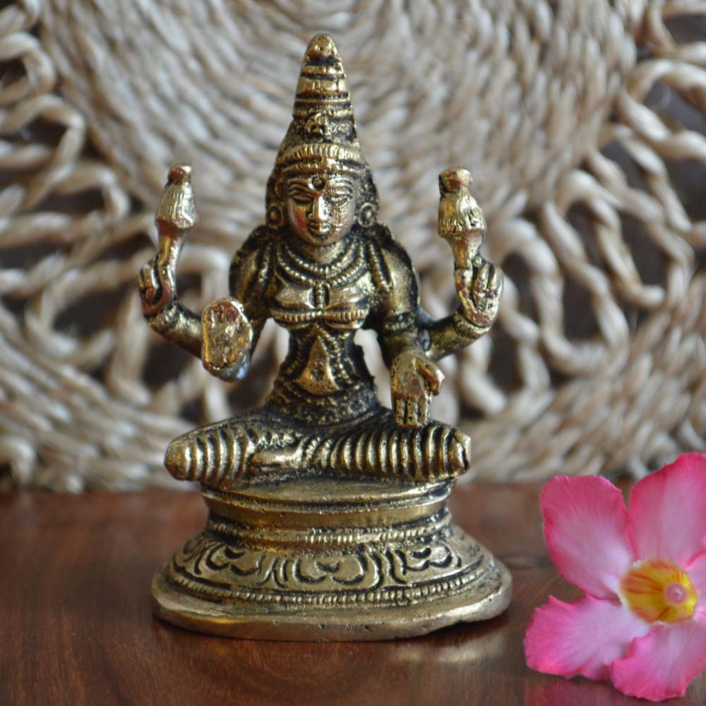 Handcrafted brass Lakshmi idol with intricate detailing, symbolizing prosperity and grace, placed on a wooden surface with floral decor.