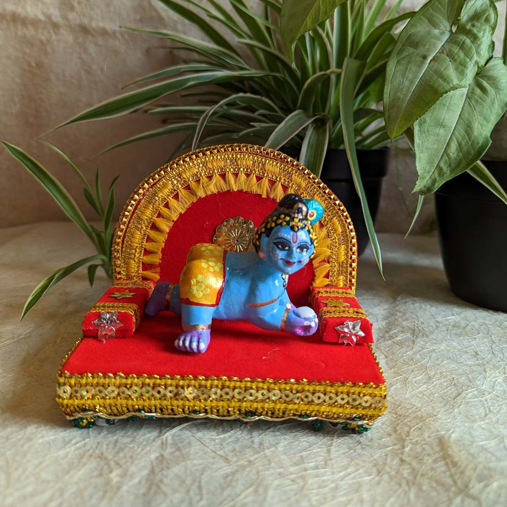 Handcrafted Crawling Krishna idol on a decorated Simhasan with red and gold accents.