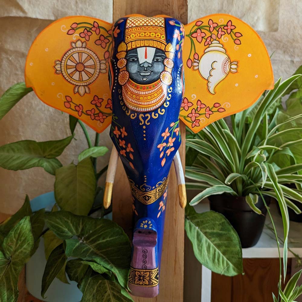 Hand-painted decorative wooden elephant head with intricate floral designs and vibrant Indian folk art in blue, gold, and orange tones.