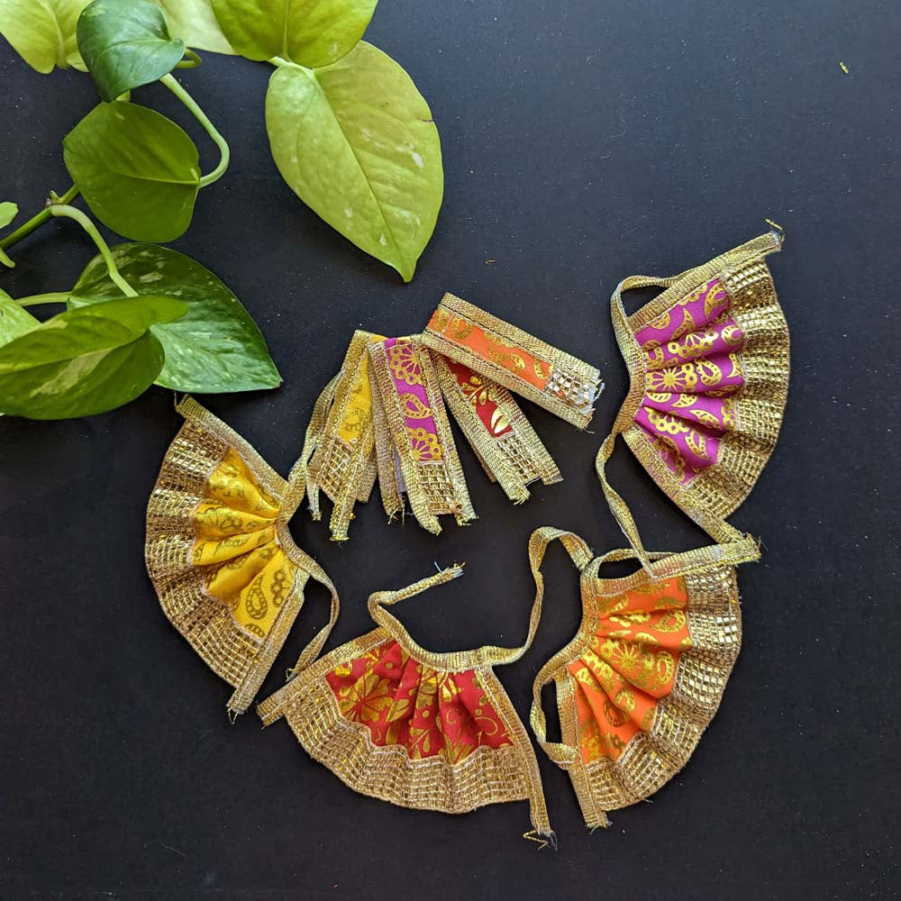 Set of traditional Devi skirts in vibrant colors with golden borders and intricate patterns, displayed on a black background with green leaves.
