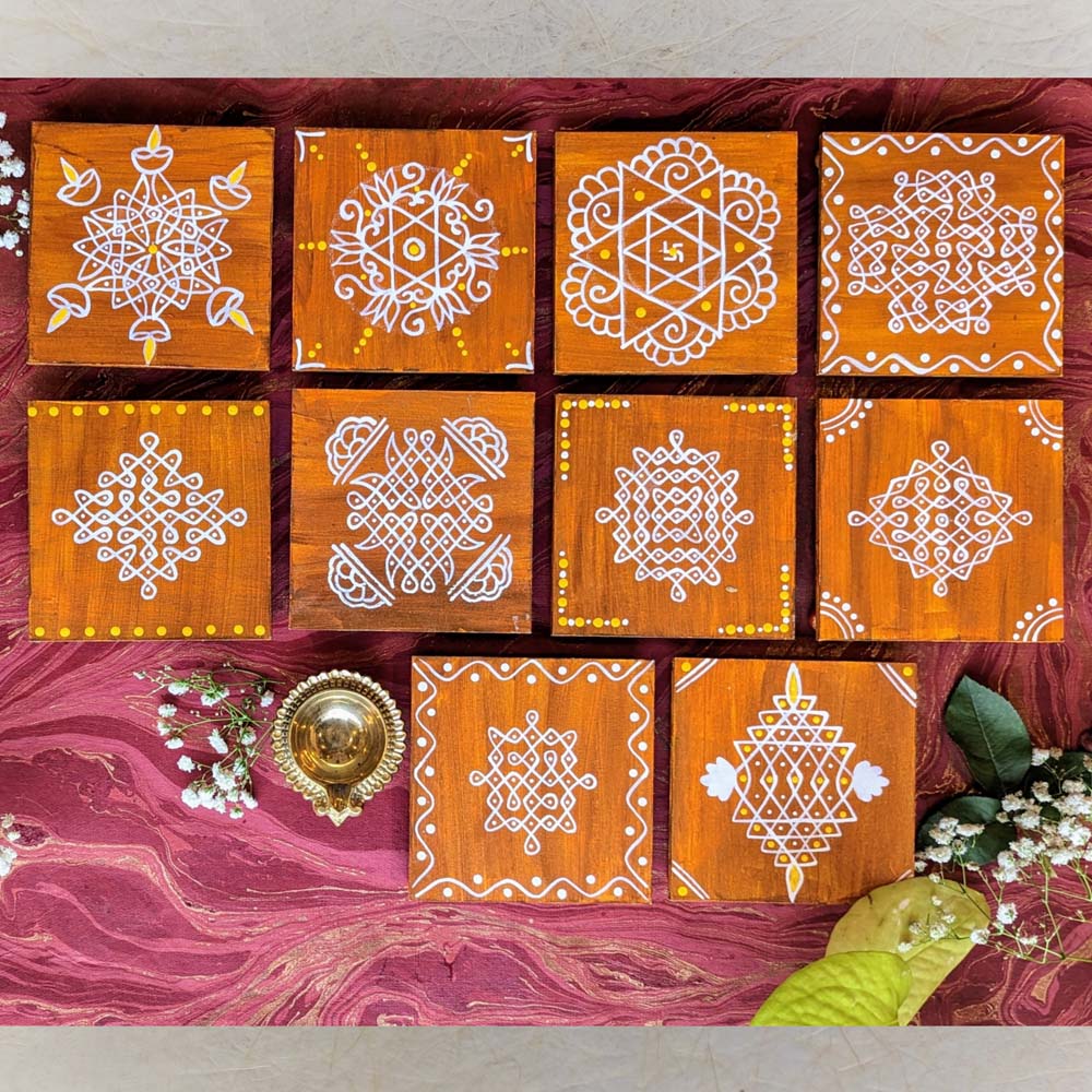 Handcrafted wooden manai set with traditional kolam designs in white, adorned with subtle decorative accents, placed on a vibrant background.