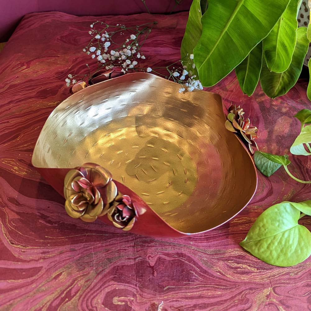 Handcrafted large metal urli bowl with red rose embellishments, golden hammered interior, and rich red exterior.