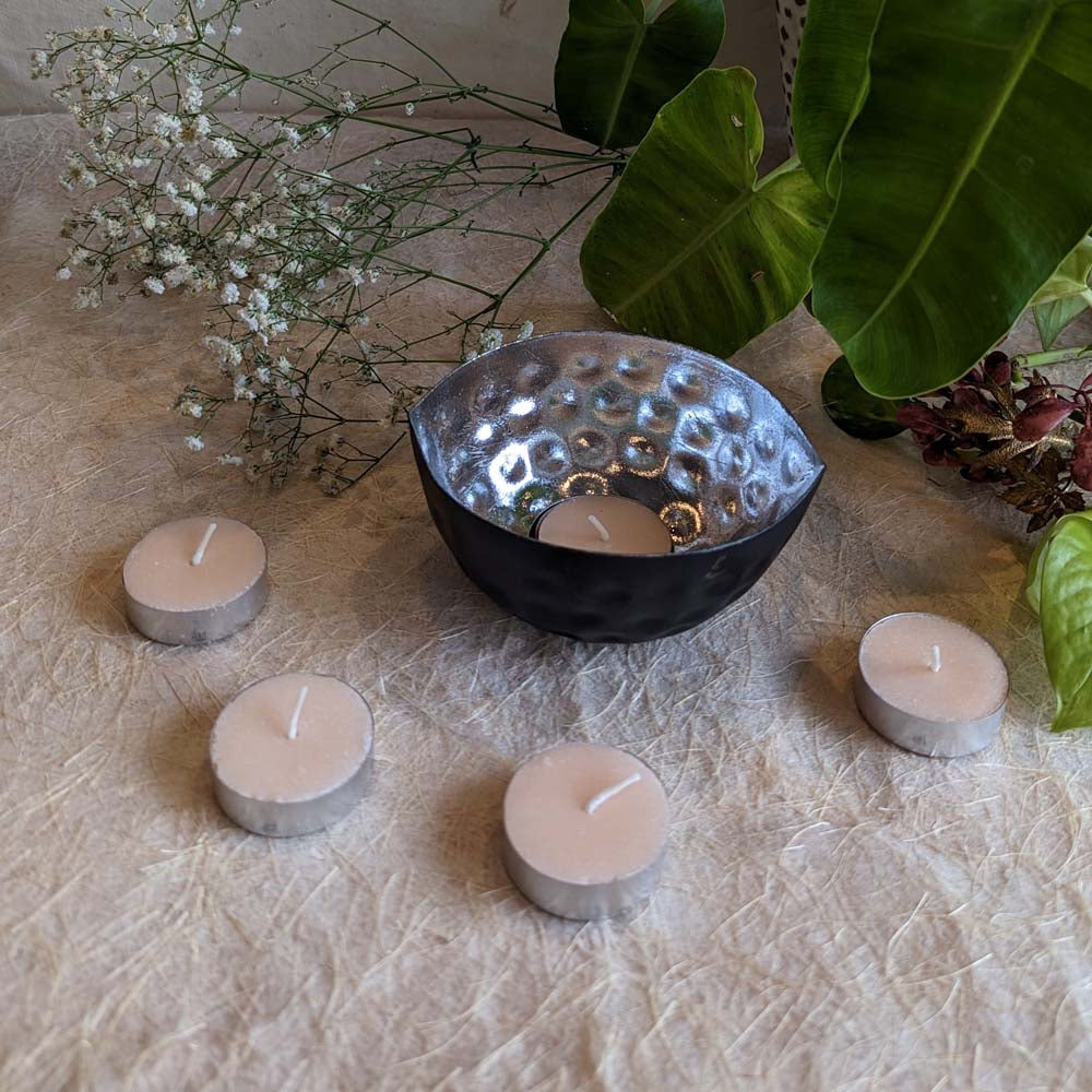 Handcrafted eye-shaped tealight holder with a hammered silver interior and matte black exterior, surrounded by tealights and natural decor.