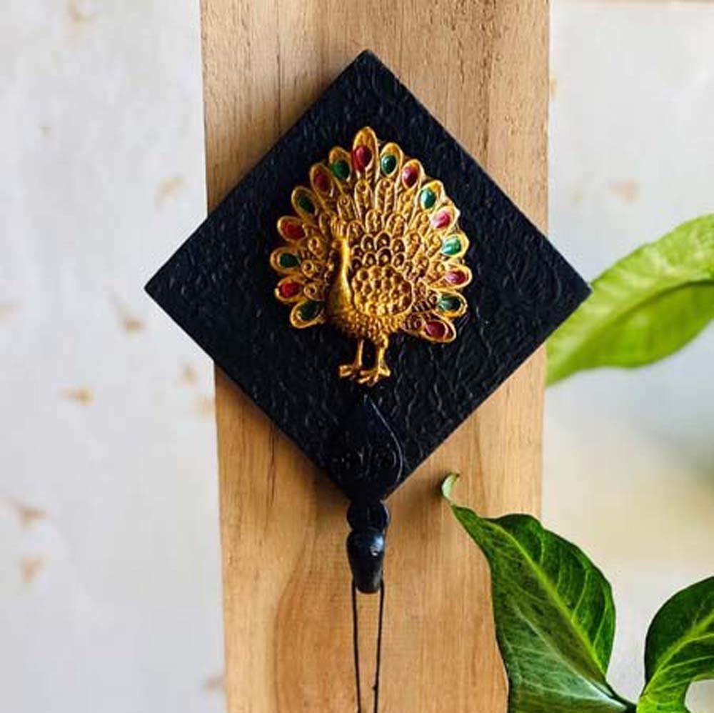 Handcrafted black key holder with a golden peacock motif featuring vibrant green and red accents.