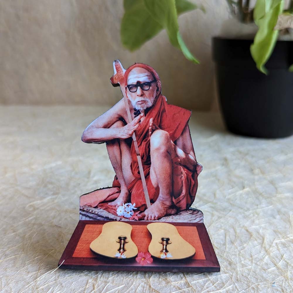 Decorative tabletop stand featuring Kanchi Maha Periyava with miniature padukas, ideal for pooja rooms or spiritual decor.