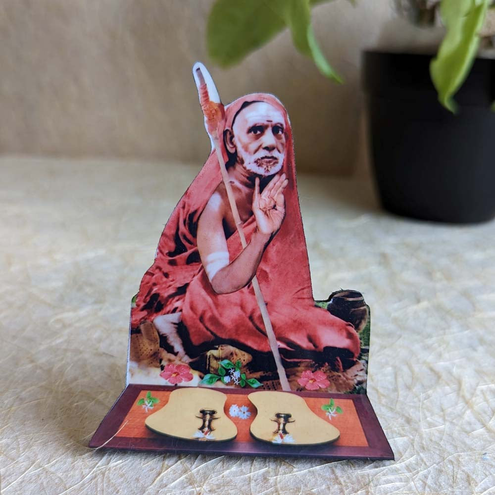 Decorative tabletop stand featuring Kanchi Maha Periyava with padukas, ideal for pooja rooms and spiritual decor.