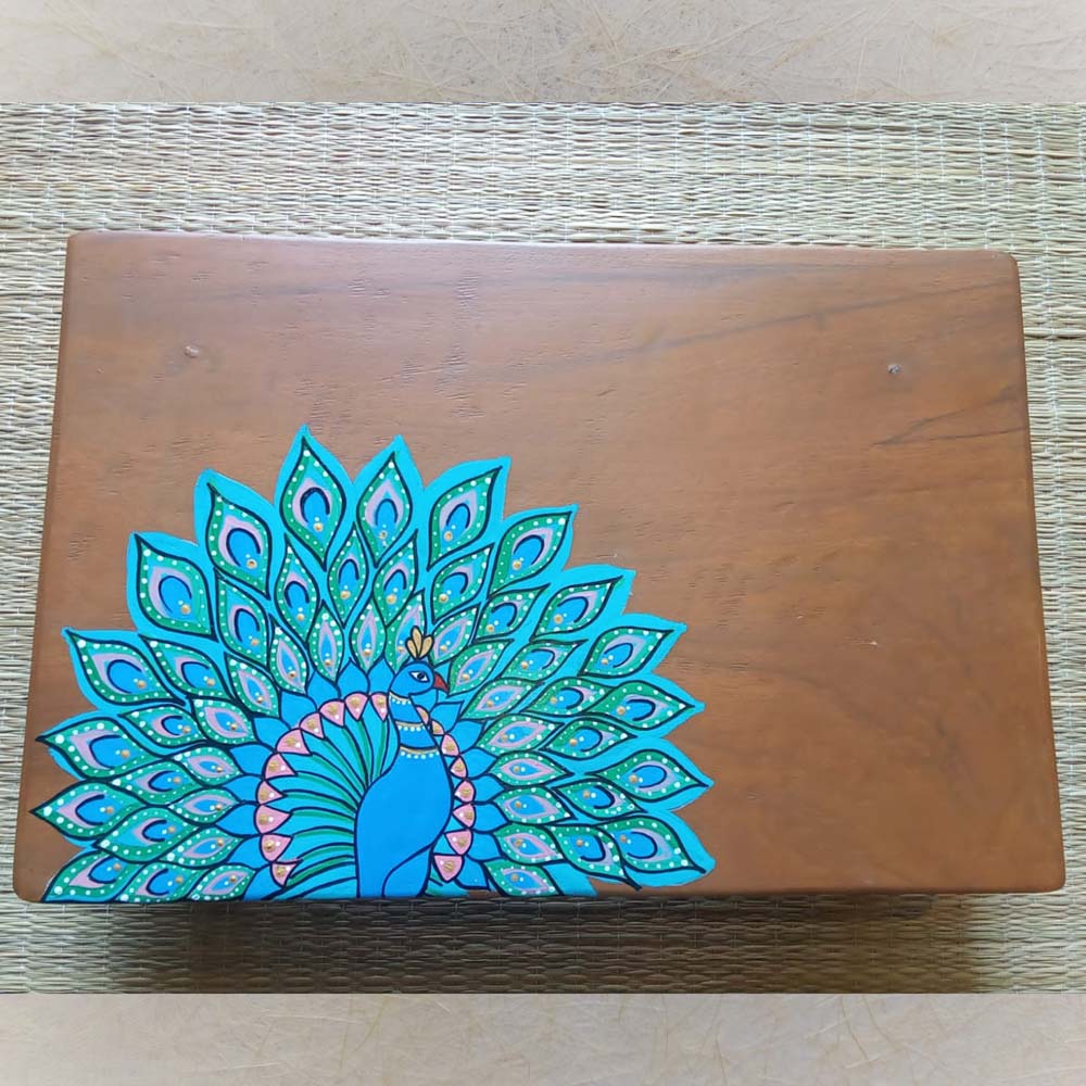 Handcrafted peacock artwork on polished Padauk wood with vibrant blue and green peacock feathers.