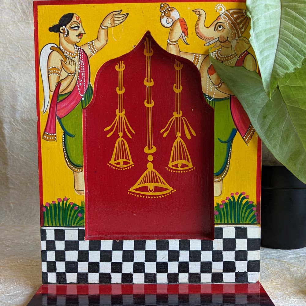 Hand-painted wooden wall shelf with yellow and blue tones, featuring elephant motifs, black-and-white checkered patterns, and a traditional arched design.